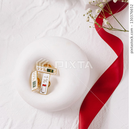 Unique gold pins displayed on soft white surface with decorative ribbon Unique gold pins displayed on soft white surface with decorative ribbon 130376652