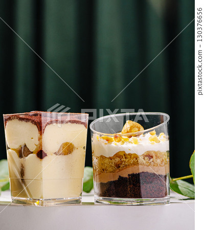 Desserts in clear glasses with layers of cream and chocolate on a table Desserts in clear glasses with layers of cream and chocolate on a table 130376656