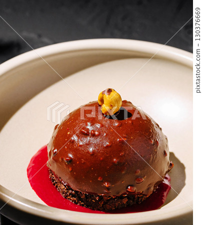 Delicious dessert presented in an elegant dish with chocolate and berry sauce 130376669