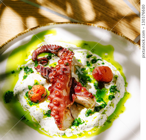 Grilled octopus served on a bed of creamy sauce with fresh herbs Grilled octopus served on a bed of creamy sauce with fresh herbs 130376680