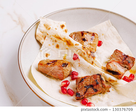 Grilled meat with pomegranate on flatbread served in a bowl Grilled meat with pomegranate on flatbread served in a bowl 130376709