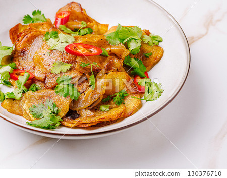 Crispy potato dish with herbs and chili garnishing on a white plate 130376710