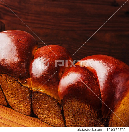 Freshly baked bread resting on wooden surface with golden crust Freshly baked bread resting on wooden surface with golden crust 130376731