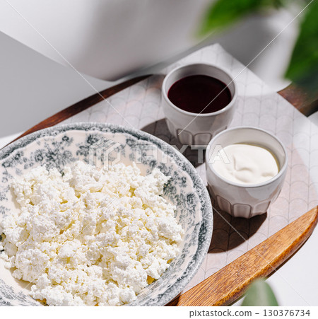 Delicious cottage cheese served with honey and sour cream on a wooden tray Delicious cottage cheese served with honey and sour cream on a wooden tray 130376734