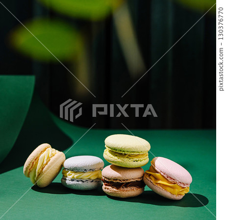 Colorful macarons arranged artfully on a green surface in a bright setting Colorful macarons arranged artfully on a green surface in a bright setting 130376770