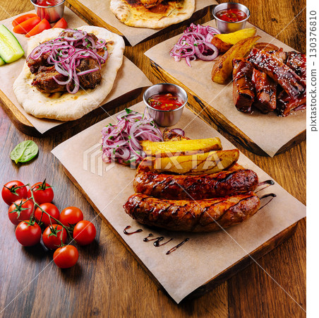 Delicious grilled meats and fresh ingredients served on a wooden table Delicious grilled meats and fresh ingredients served on a wooden table 130376810