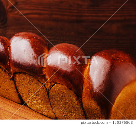 Freshly baked bread loaf on a wooden surface showcasing golden crust Freshly baked bread loaf on a wooden surface showcasing golden crust 130376868