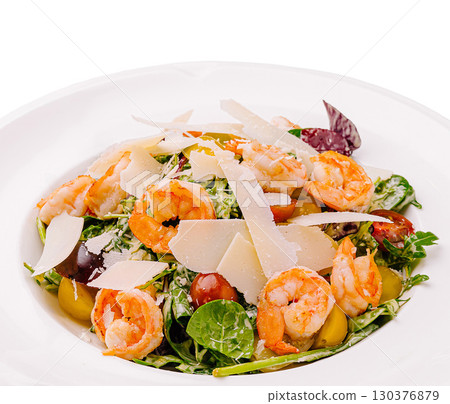Fresh shrimp salad with greens and cheese served on a white plate 130376879