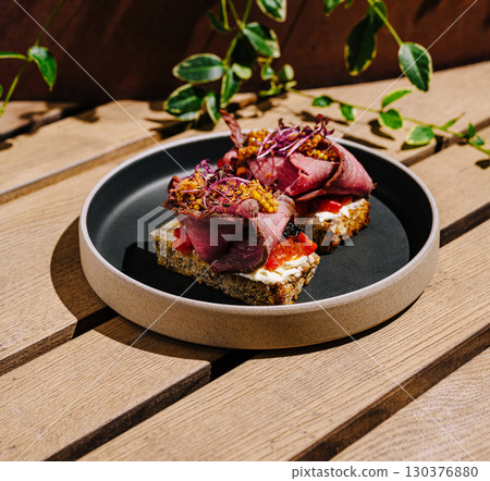 Two open-faced sandwiches are served on a round plate 130376880