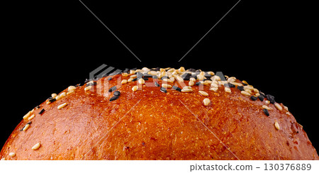 Freshly baked sesame seed bun with glossy finish on a black background 130376889
