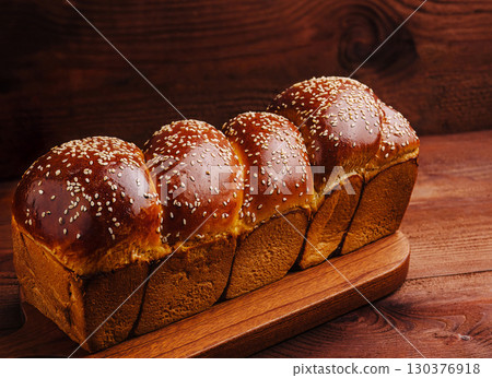 Freshly baked sesame topped bread loaf on a wooden board 130376918