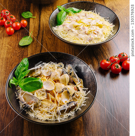 Gourmet pasta dishes served on wooden table with fresh ingredients Gourmet pasta dishes served on wooden table with fresh ingredients 130376928
