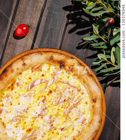 Delicious pizza topped with cheese and ham on a rustic wooden ta Delicious pizza topped with cheese and ham on a rustic wooden ta 130376948