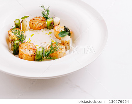 Elegant scallop dish with garnishes in fine dining setting 130376964