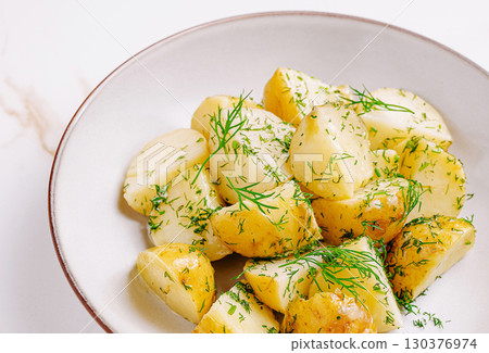 Delicious boiled potatoes with fresh herbs served in a white bowl 130376974