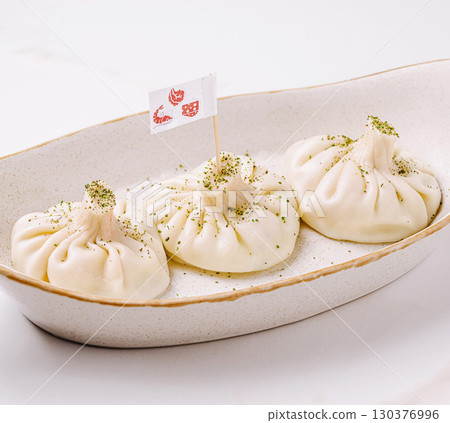 Delicious dumplings served on a white platter with unique garnishes Delicious dumplings served on a white platter with unique garnishes 130376996