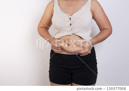 Overweight woman hand pinching excessive belly fat on gray background, Healthy concept Overweight woman hand pinching excessive belly fat on gray background, Healthy concept 130377008