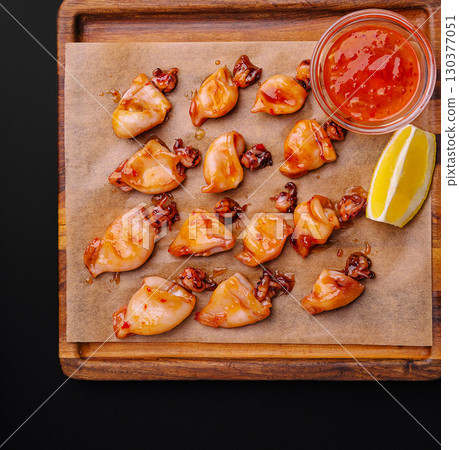 Grilled seafood delicacies served with spice sauce and lemon wedges 130377051