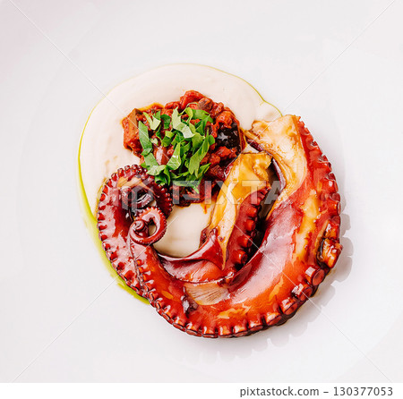 Deliciously cooked octopus served elegantly on a white plate wit 130377053