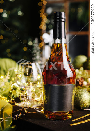 Festive table arrangement with a bottle of liquor and holiday decorations 130377069