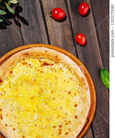 Delicious cheese pizza placed on wooden table with fresh tomatoes 130377090
