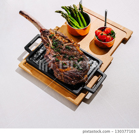 Juicy ribeye steak served with roasted tomatoes and grilled asparagus 130377103