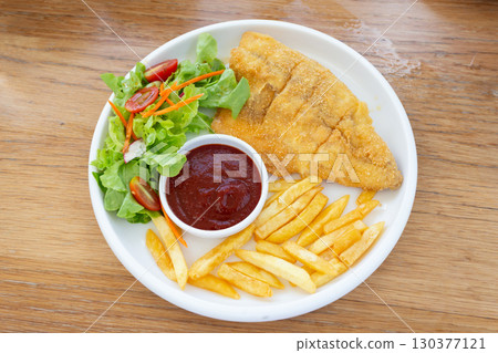 Fish steak with vegetable salad and french fries on a plate, top view Fish steak with vegetable salad and french fries on a plate, top view 130377121