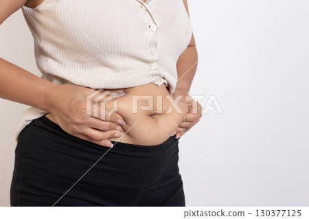 Overweight woman hand pinching excessive belly fat on gray background, Healthy concept Overweight woman hand pinching excessive belly fat on gray background, Healthy concept 130377125