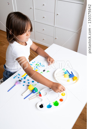 Young caucasian child engaging in creative paint activity with sponge brushes at home Young caucasian child engaging in creative paint activity with sponge brushes at home 130379842