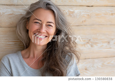 Middle-aged woman with long wavy hair smiling warmly in a bright indoor setting 130380838