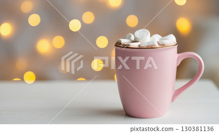 Pink mug filled with hot chocolate and marshmallows against a cozy Christmas background with warm glowing lights Pink mug filled with hot chocolate and marshmallows against a cozy Christmas background with warm glowing lights 130381136