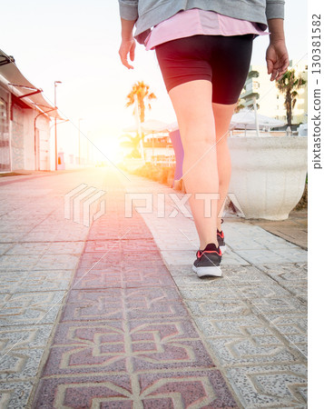 Person walking on a sunny paved path 130381582
