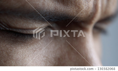 Individual conveys intense sorrow with tightly closed eyes, reflecting a moment of emotional struggle 130382068