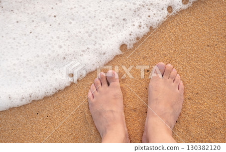 Female feet barefoot in waves of foamy water on a sandy beach. View of female feet, woman on the beach getting her feet wet in warm sea water, carefree holiday by the sea. Relaxing on beautiful beach Female feet barefoot in waves of foamy water on a sandy beach. View of female feet, woman on the beach getting her feet wet in warm sea water, carefree holiday by the sea. Relaxing on beautiful beach 130382120