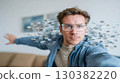 Young man with glasses is reaching out with hand, surrounded by digital elements, illustrating technology and innovation in a modern environment 130382220