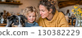 Woman and child enjoying cozy moment with dog at home, sharing warmth and connection in a beautifully decorated kitchen environment 130382229