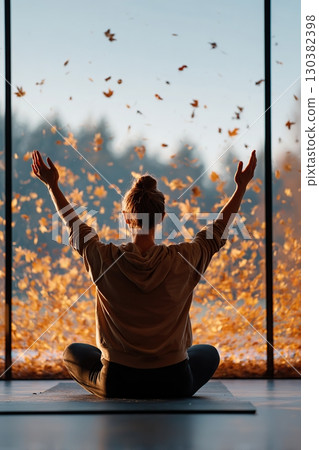 Stretching and embracing tranquility in a serene indoor space surrounded by autumn leaves 130382398