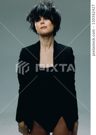 Stylish woman with short black hair wearing a black blazer against a neutral background, exuding modern confidence and minimalistic elegance. Stylish woman with short black hair wearing a black blazer against a neutral background, exuding modern confidence and minimalistic elegance. 130382427