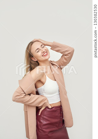 Laughing caucasian female adult in pink blazer and red skirt posing happily 130382530