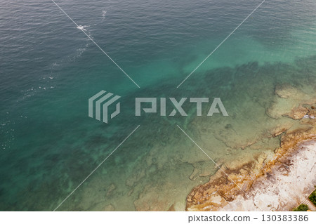 Aerial rocky shoreline with turquoise sea waters 130383386