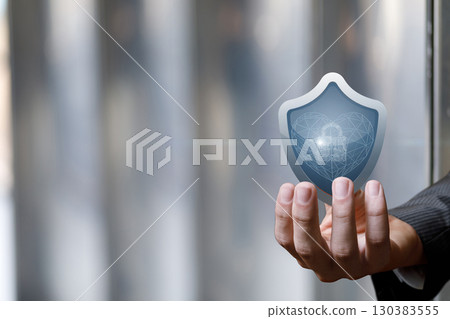 Hand holding a digital shield symbolizing security and protection. 130383555