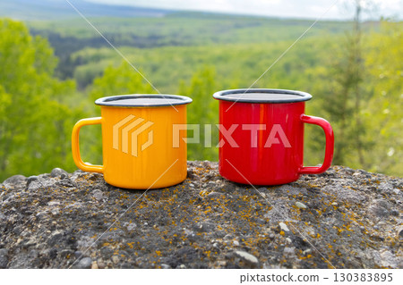Colorful camping Cups on Rocks Overlooking Valley Colorful camping Cups on Rocks Overlooking Valley 130383895