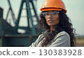 Black female oilfield technician is at work near pumpjack. 130383928