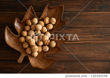 Maple Leaf Wooden Bowl with Walnuts on Rustic Table. Top view Maple Leaf Wooden Bowl with Walnuts on Rustic Table. Top view 130384108