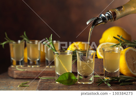 Italian liqueur Limoncello with fresh lemons and rosemary branches. 130384273