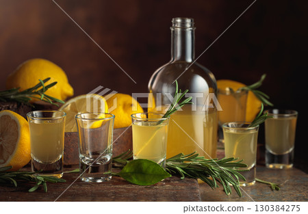 Italian liqueur Limoncello with fresh lemons and rosemary branches. Italian liqueur Limoncello with fresh lemons and rosemary branches. 130384275