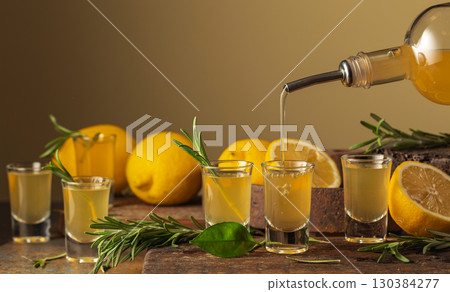 Italian liqueur Limoncello with fresh lemons and rosemary branches. Italian liqueur Limoncello with fresh lemons and rosemary branches. 130384277