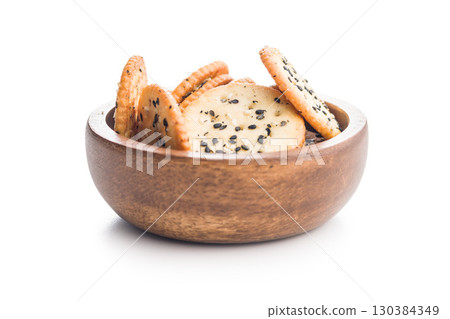 Crispy round salted crackers with sesame seeds in bowl isolated on white background. Crispy round salted crackers with sesame seeds in bowl isolated on white background. 130384349