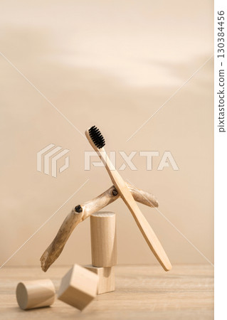 Eco bamboo toothbrush with black bristles balanced on natural wood decor 130384456