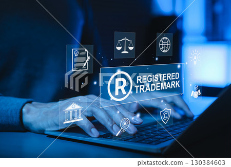 Registered trademark protection and intellectual property concept. Hands typing on laptop with icons registered trademark, legal protection, intellectual property rights, global business regulation, 130384603